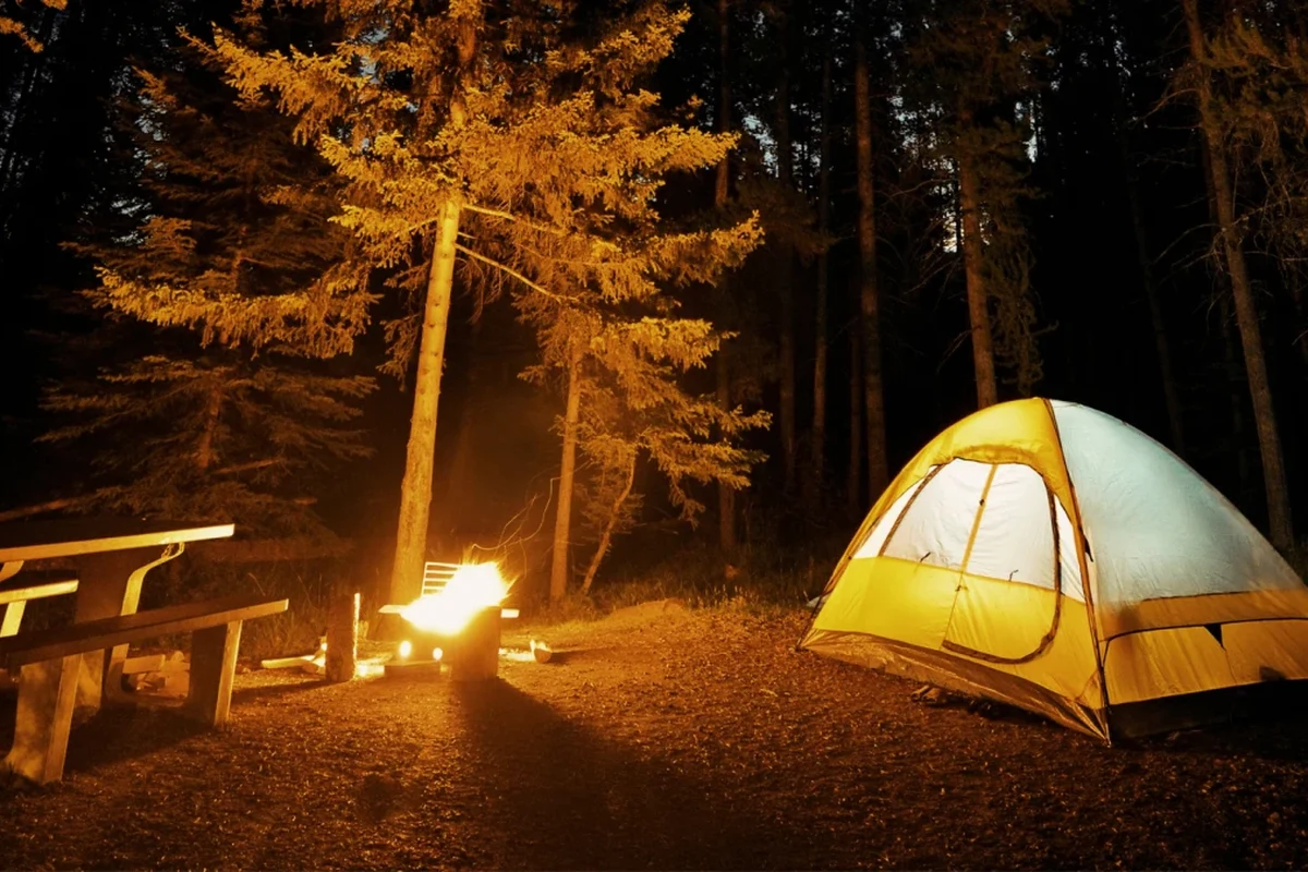 Person folding a sleeping bag neatly on a clean surface for camping storage