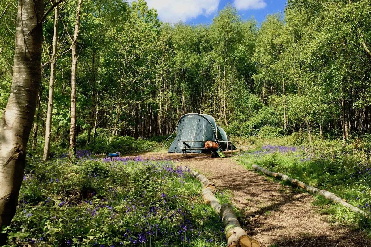 Person rolling a sleeping bag on a clean surface for camping storage