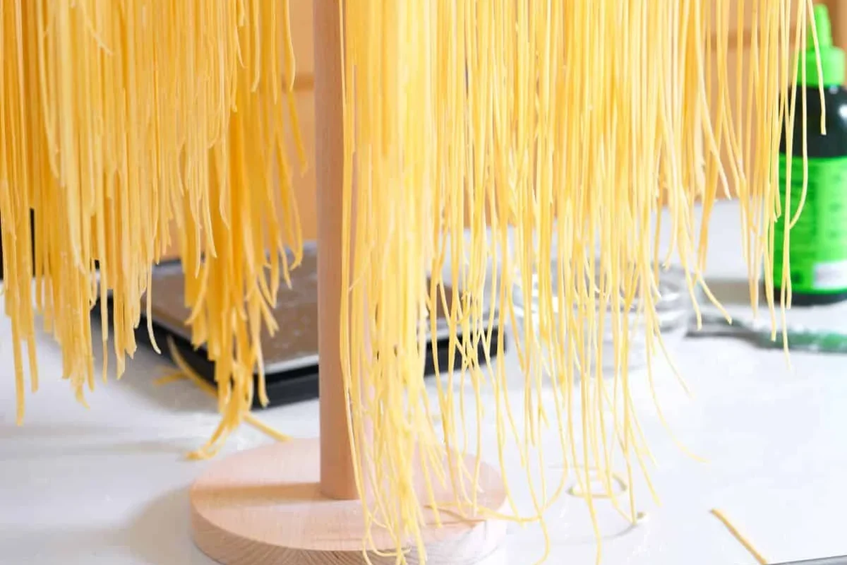 Homemade dried pasta stored in a sealed pantry container beside a kitchen towel